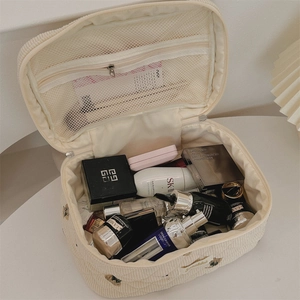 Detail view of beige corduroy cosmetic bag with floral embroidery and mesh organizer