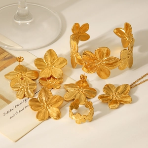 Detailed set of gold flower earrings, necklace, bracelet and ring on aesthetic background