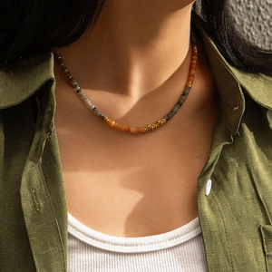 Detail of colorful bohemian beaded necklace with grey and orange stones on a model