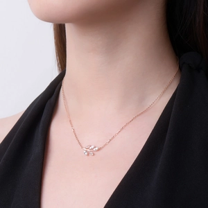 Close-up of rose gold leaf pendant necklace with moissanite stones on a female model