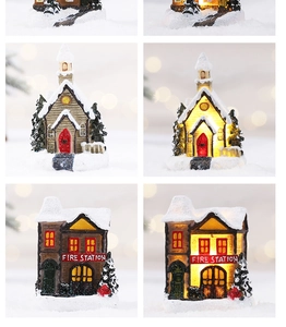 Miniature snowy Christmas houses and fire station with glowing LED festive lights