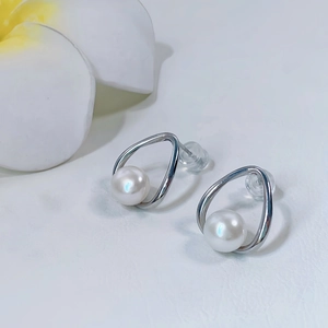 Dettaglio macro di orecchini a nodo in argento con perle d'acqua dolce e chiusure in silicone