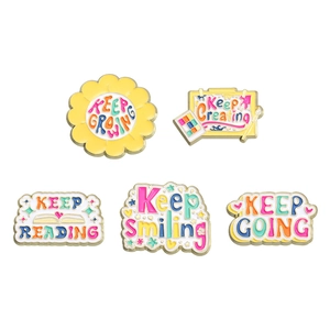Set of 5 colorful enamel inspirational badges with gold metal outlines on white background