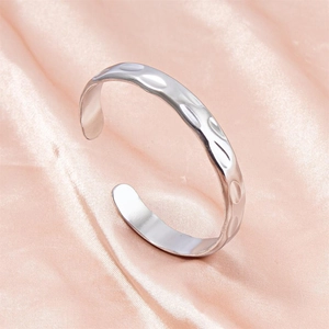 Silver stainless steel open cuff bracelet featuring an irregular hammered texture on silk