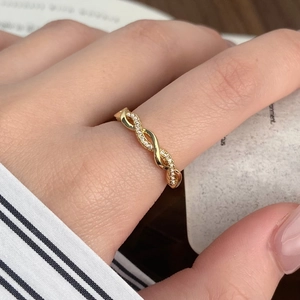 Macro detail of a twisted gold zircon ring with pavé micro-setting on a hand