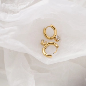 Detailed macro view of 18K gold-plated titanium earrings with sparkling clear cubic zirconia
