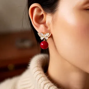 Elegant gold butterfly earrings with sparkling crystals and a red pearl drop pendant