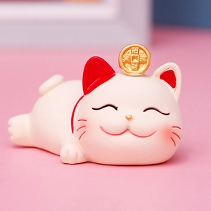 Close-up of white ceramic lucky cat figurine with gold coin and red collar details