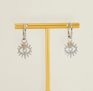 Detail of silver stainless steel evil eye earrings with orange bead on a jewelry stand
