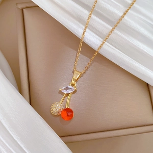 Macro shot of a cherry pendant necklace with red beads and crystal leaves on a jewelry box
