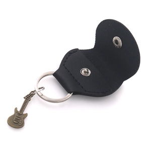 Detail of black leather guitar pick pouch with metallic snap and guitar charm keychain