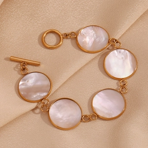 Flat lay of an 18K gold-plated OT buckle bracelet with round mother-of-pearl charms