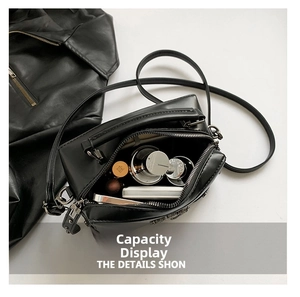 Interior view showing capacity of black leather crossbody bag with makeup and phone