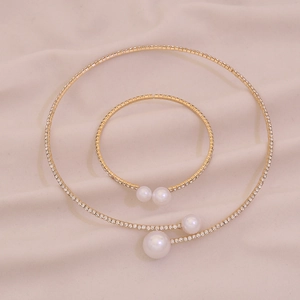 Detail of gold pearl necklace and bracelet set with rhinestones on beige fabric