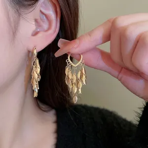 Exaggerated golden leaf tassel earrings with layered metal pendants and luxurious finish