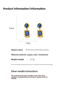 Detail view of vintage gold earrings with blue resin stones and 925 silver needles