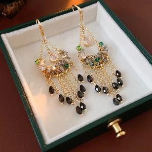 Close-up of vintage gold tassel earrings with green zircon in a luxury jewelry box