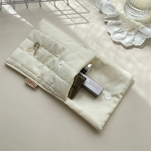 Detail of cream quilted fabric storage bag with exquisite rabbit embroidery and snap button