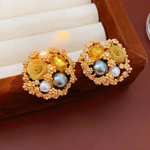 Détail de boucles d'oreilles vintage dorées avec perles et gemmes dans une boîte en velours