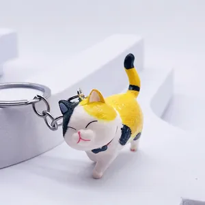 Detail of calico cat keychain with a black bow tie on a minimalist white background
