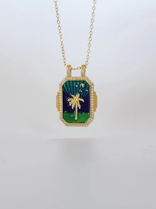 Detailed macro view of gold tarot card pendant featuring palm tree and white crystals