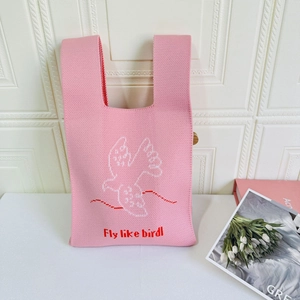 Close-up of pink knitted tote bag showing soft texture and Fly Like Bird embroidery