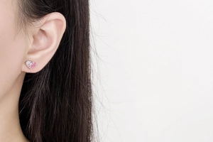 Close-up of pink and clear heart-shaped zircon earrings worn on a model's ear