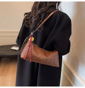 Brown vintage crescent bag on shoulder with smiley charm and PU leather texture