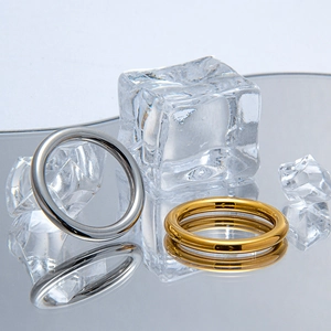 Minimalist 2.5mm stainless steel rings in silver and gold on a reflective icy surface