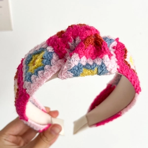 Detail of hand-crocheted floral headband showing colorful knit textures and knotted design