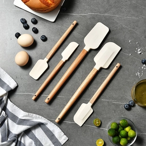 Five-piece silicone spatula set with wooden handles on a marble surface for baking