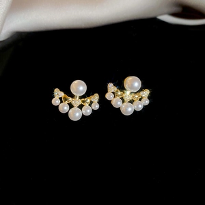 Detailed macro of gold pearl earrings with sparkling micro zircons on black velvet