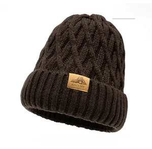 Detail of coffee brown knit beanie showing diamond cable pattern and leather brand patch