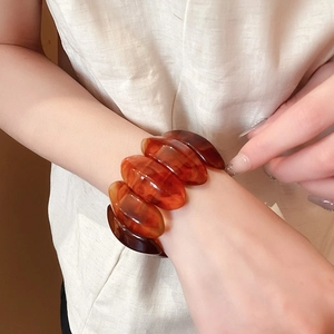 Close-up of amber resin bangle featuring marble patterns on a model's wrist