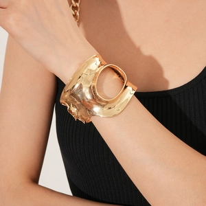 Détail d'un large bracelet doré géométrique avec texture lave et design ajouré rond