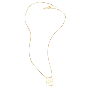 Macro detail of gold box chain and rectangular pendant with artistic Fé engraving