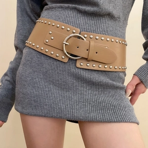 Macro shot of khaki leather waist belt featuring round silver rivets and a circular metal buckle