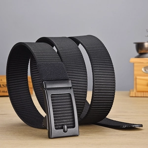 Close-up of black woven nylon belt with matte rectangular buckle on wood table