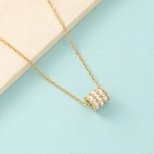 Close-up of gold-plated cylinder pendant necklace featuring three rows of sparkling zircons