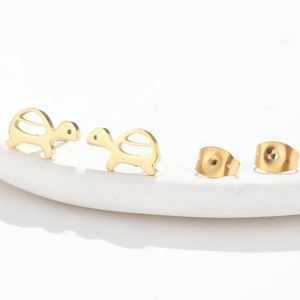 Detail view of golden turtle stud earrings with matching metal backs on white background