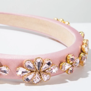 Vue détaillée du serre-tête en satin rose avec fleurs en strass et griffes en métal doré