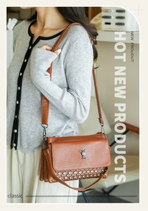 Close-up of brown soft leather crossbody bag with metal rivets and rabbit pendant charm