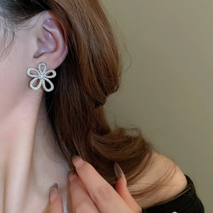 Macro view of sparkling floral crystal earring on model with detailed openwork design