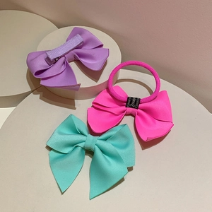 Detailed view of colorful neon bow hair clips and elastic tie on a white podium