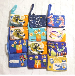 Flat lay of colorful handmade wool felt pouches featuring flower and art embroidery