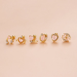 Lot de six boucles d'oreilles cœur dorées avec zircons roses sur fond rose