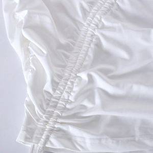 Detailed view of white bodycon dress featuring drawstring ruching and textured fabric