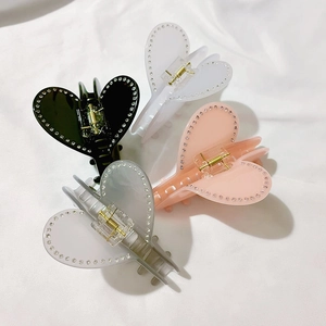 Dettaglio di quattro mollette a cuore in acetato nero, bianco, rosa e grigio con strass