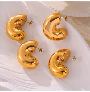 Macro view of minimalist 18K gold plated thick C-shaped hoop earrings on ceramic