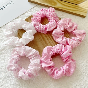 Set of five floral and checkered pink scrunchies arranged on a minimalist wooden tray